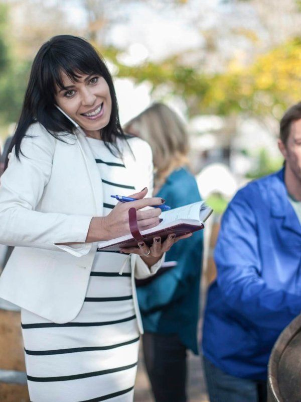 Wine saleswoman with group of clients outdoors and wine worker with barrel
