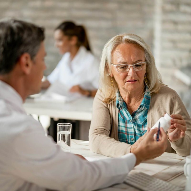 Senior woman consulting with healthcare worker about her prescription medicines.